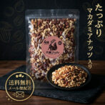 Bag of four-nut mix with a pink circular label, placed beside a bowl of roasted nuts on a dark wooden surface.